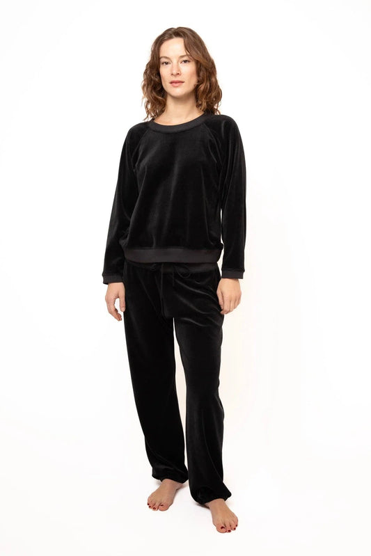 Woman wearing a black velvet pajama set on a white background